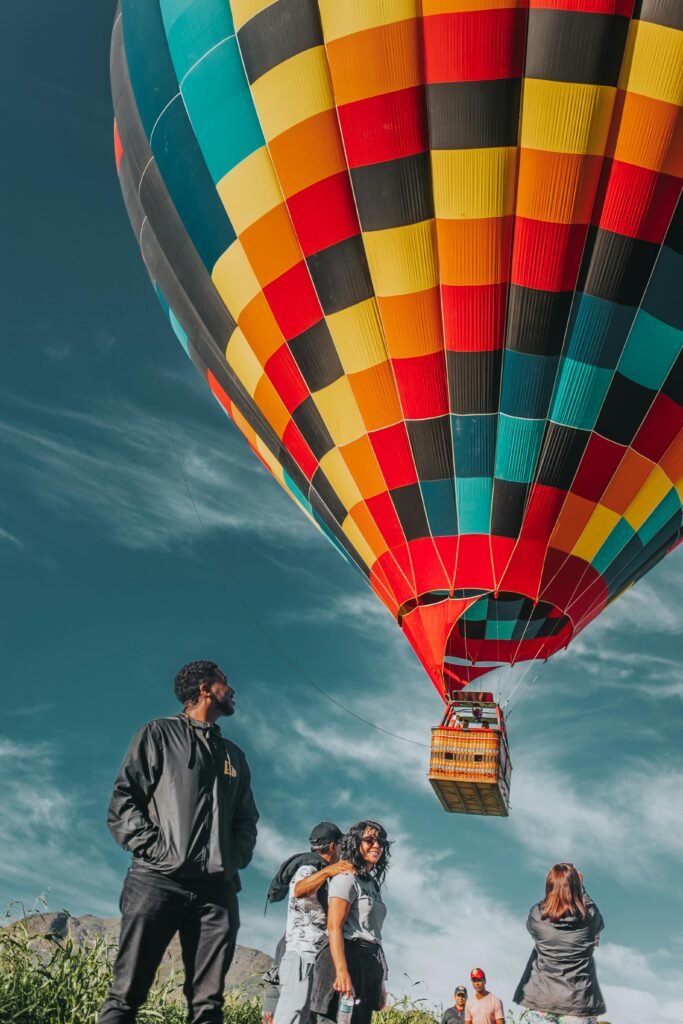 A colorful hot air balloon soars above a group enjoying the thrill of outdoor adventure - perks of investing in startups