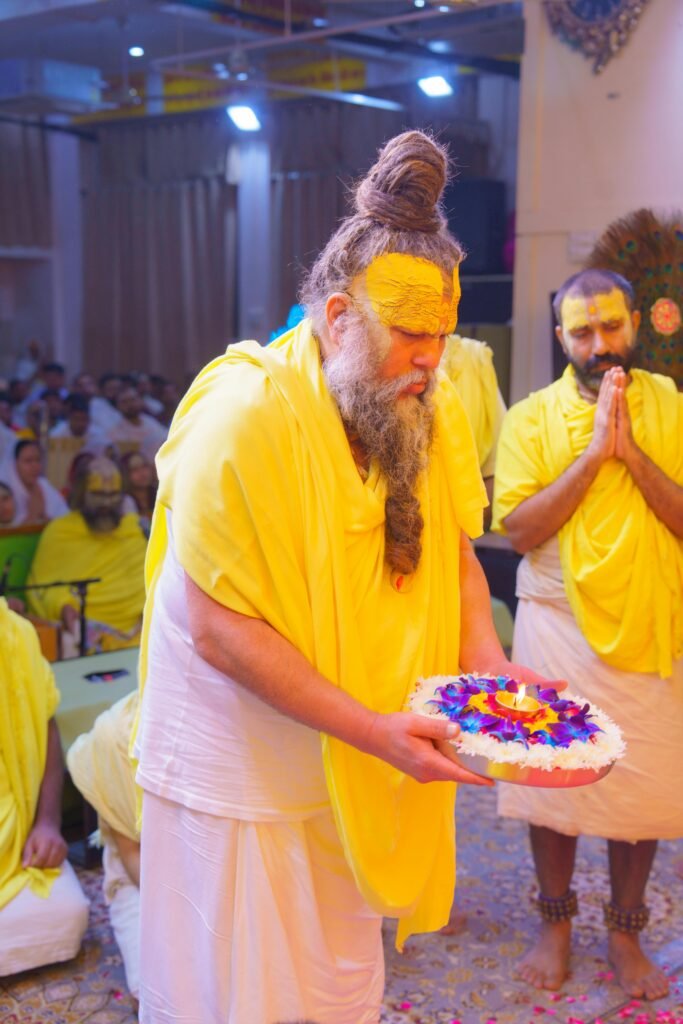 A vibrant Hindu ritual in Vrindavan, India, featuring a ceremonial floral offering by participants in yellow attire.