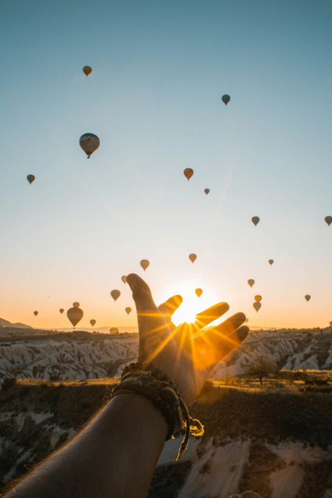 Experience the magic of hot air balloons at sunrise with an outstretched hand in Cappadocia's breathtaking landscape.-investin