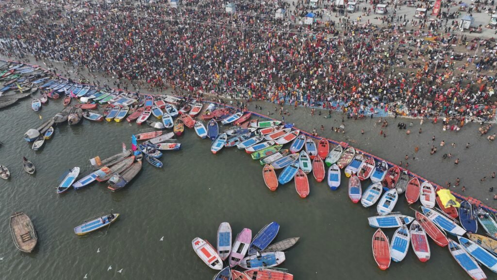 Aerial shot showcasing the bustling crowd and colorful boats at Kumbh Mela in Prayagraj - signifying size of   religious market